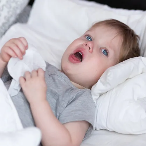 Μικρό παιδί στο κρεβάτι βήχει