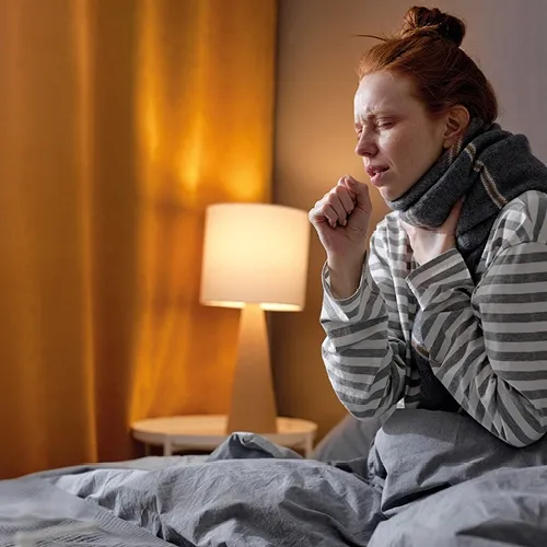 Γυναίκα στο κρεβάτι που βήχει
